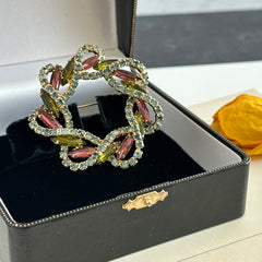 Vintage gold tone wreath brooch with amethyst, peridot, and blue rhinestones, shown in various decorative arrangements.