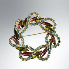 Vintage gold tone wreath brooch with amethyst, peridot, and blue rhinestones, shown in various decorative arrangements.