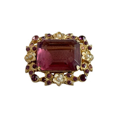 Vintage gold‑tone brooch with an amethyst‑colored rhinestone, faux pearls, and white enamel flowers