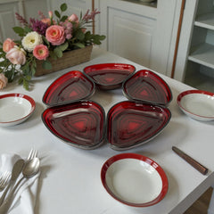 Vintage Anchor Hocking Royal Ruby relish trays arranged in a circular pattern around a coordinating red glass plate. The translucent ruby red glass glows with depth and symmetry, showcasing the sculptural triangular shapes and rich mid-century color. Ideal for holiday styling or vintage table settings.