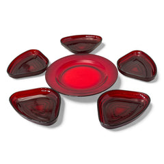 Vintage Anchor Hocking Royal Ruby relish trays arranged in a circular pattern around a coordinating red glass plate. The translucent ruby red glass glows with depth and symmetry, showcasing the sculptural triangular shapes and rich mid-century color. Ideal for holiday styling or vintage table settings.