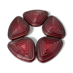 Vintage Anchor Hocking Royal Ruby relish trays arranged in a circular pattern around a coordinating red glass plate. The translucent ruby red glass glows with depth and symmetry, showcasing the sculptural triangular shapes and rich mid-century color. Ideal for holiday styling or vintage table settings.