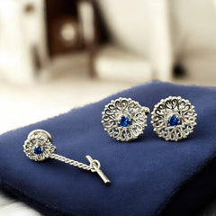 Vintage Anson men’s jewelry set featuring silver-tone round cufflinks and matching tie tack with blue rhinestones and openwork filigree design; presented in original moss green velvet-lined box, all pieces signed and in excellent condition.