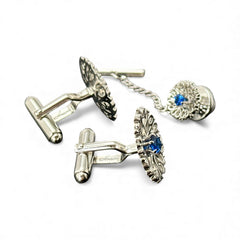 Vintage Anson men’s jewelry set featuring silver-tone round cufflinks and matching tie tack with blue rhinestones and openwork filigree design; presented in original moss green velvet-lined box, all pieces signed and in excellent condition.