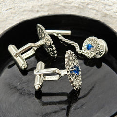 Vintage Anson men’s jewelry set featuring silver-tone round cufflinks and matching tie tack with blue rhinestones and openwork filigree design; presented in original moss green velvet-lined box, all pieces signed and in excellent condition.