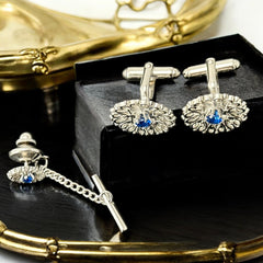 Vintage Anson men’s jewelry set featuring silver-tone round cufflinks and matching tie tack with blue rhinestones and openwork filigree design; presented in original moss green velvet-lined box, all pieces signed and in excellent condition.
