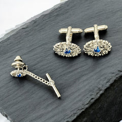 Vintage Anson men’s jewelry set featuring silver-tone round cufflinks and matching tie tack with blue rhinestones and openwork filigree design; presented in original moss green velvet-lined box, all pieces signed and in excellent condition.