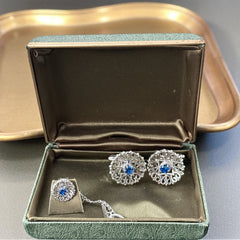 Vintage Anson men’s jewelry set featuring silver-tone round cufflinks and matching tie tack with blue rhinestones and openwork filigree design; presented in original moss green velvet-lined box, all pieces signed and in excellent condition.