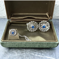 Vintage Anson men’s jewelry set featuring silver-tone round cufflinks and matching tie tack with blue rhinestones and openwork filigree design; presented in original moss green velvet-lined box, all pieces signed and in excellent condition.
