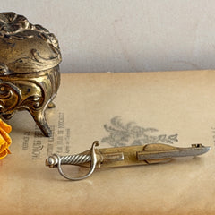 Vintage Anson gold‑tone sword tie clip with silver‑tone grip and engraved details