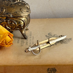 Vintage Anson gold‑tone sword tie clip with silver‑tone grip and engraved details