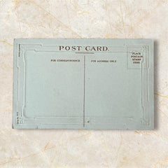 Antique 1910s embossed postcard featuring a snowy path with a person and child walking, framed by gilded orange-brown border; message reads “All Good Wishes for the New Year.