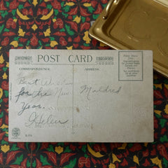 Antique 1912 New Year postcard featuring embossed deer in snowy forest with pinecones and gold gilt, muted lavender background, greeting “A Happy New Year” in capital letters, very good condition with minimal corner wear.