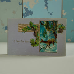 Antique 1912 New Year postcard featuring embossed deer in snowy forest with pinecones and gold gilt, muted lavender background, greeting “A Happy New Year” in capital letters, very good condition with minimal corner wear.