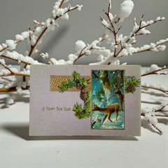 Antique 1912 New Year postcard featuring embossed deer in snowy forest with pinecones and gold gilt, muted lavender background, greeting “A Happy New Year” in capital letters, very good condition with minimal corner wear.