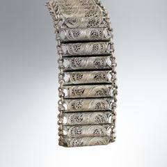 Antique Balkan cannetille silver bracelet with ornate filigree links, side chains, and a long pin clasp, shown in its natural patina.