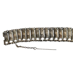Antique Balkan cannetille silver bracelet with ornate filigree links, side chains, and a long pin clasp, shown in its natural patina.