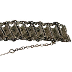 Antique Balkan cannetille silver bracelet with ornate filigree links, side chains, and a long pin clasp, shown in its natural patina.