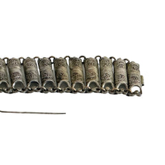 Antique Balkan cannetille silver bracelet with ornate filigree links, side chains, and a long pin clasp, shown in its natural patina.