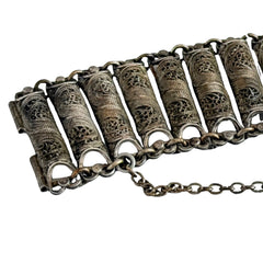 Antique Balkan cannetille silver bracelet with ornate filigree links, side chains, and a long pin clasp, shown in its natural patina.