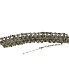 Antique Balkan cannetille silver bracelet with ornate filigree links, side chains, and a long pin clasp, shown in its natural patina.