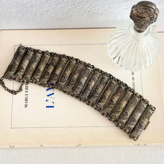 Antique Balkan cannetille silver bracelet with ornate filigree links, side chains, and a long pin clasp, shown in its natural patina.