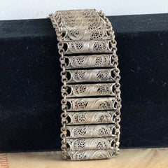 Antique Balkan cannetille silver bracelet with ornate filigree links, side chains, and a long pin clasp, shown in its natural patina.