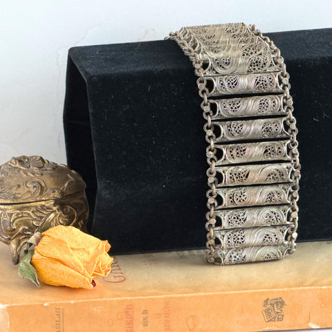 Antique Balkan cannetille silver bracelet with ornate filigree links, side chains, and a long pin clasp, shown in its natural patina.