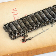 Antique Balkan cannetille silver bracelet with ornate filigree links, side chains, and a long pin clasp, shown in its natural patina.