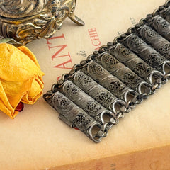 Antique Balkan cannetille silver bracelet with ornate filigree links, side chains, and a long pin clasp, shown in its natural patina.