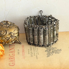 Antique Balkan cannetille silver bracelet with ornate filigree links, side chains, and a long pin clasp, shown in its natural patina.