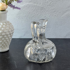 Antique pressed clear glass cruet with diamond pattern and rounded base.