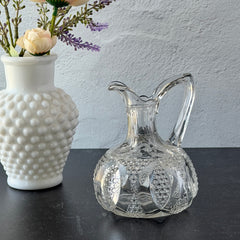 Antique pressed clear glass cruet with diamond pattern and rounded base.