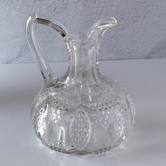 Antique pressed clear glass cruet with diamond pattern and rounded base.