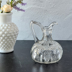 Antique pressed clear glass cruet with diamond pattern and rounded base.