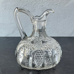 Antique pressed clear glass cruet with diamond pattern and rounded base.