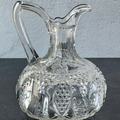 Antique pressed clear glass cruet with diamond pattern and rounded base.