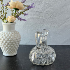 Antique pressed clear glass cruet with diamond pattern and rounded base.