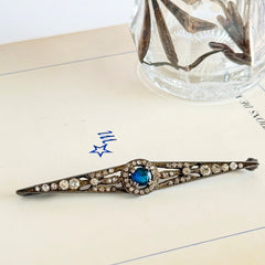 Antique French silver bar brooch with an oval Swiss‑blue topaz at the center, framed by clear stones and delicate openwork detailing.