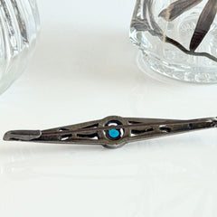 Antique French silver bar brooch with an oval Swiss‑blue topaz at the center, framed by clear stones and delicate openwork detailing.