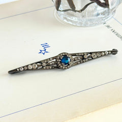 Antique French silver bar brooch with an oval Swiss‑blue topaz at the center, framed by clear stones and delicate openwork detailing.