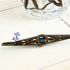 Antique French silver bar brooch with an oval Swiss‑blue topaz at the center, framed by clear stones and delicate openwork detailing.