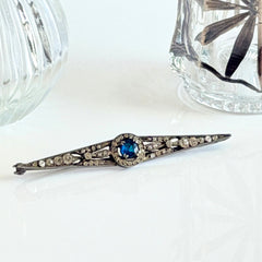 Antique French silver bar brooch with an oval Swiss‑blue topaz at the center, framed by clear stones and delicate openwork detailing.