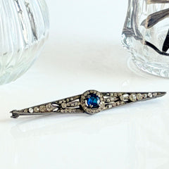 Antique French silver bar brooch with an oval Swiss‑blue topaz at the center, framed by clear stones and delicate openwork detailing.