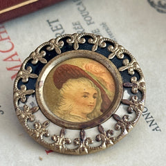 Antique Victorian portrait brooch with lithograph miniature, brass fleur‑de‑lys frame, and celluloid cover.