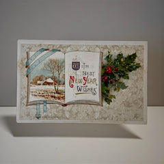 Antique embossed German New Year postcard from the 1910s featuring an open book with snowy countryside illustration, festive holly sprig, and ornate greeting text.
