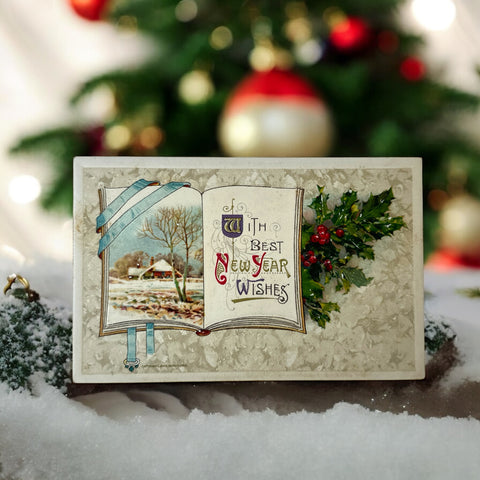 Antique embossed German New Year postcard from the 1910s featuring an open book with snowy countryside illustration, festive holly sprig, and ornate greeting text.