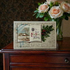 Antique embossed German New Year postcard from the 1910s featuring an open book with snowy countryside illustration, festive holly sprig, and ornate greeting text.