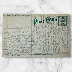 Antique 1913 New Year postcard featuring embossed four-leaf clovers, gilded scroll with greeting, and red seal motif; preserved message on reverse, marked Made in Saxony.