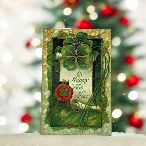 Antique 1913 New Year postcard featuring embossed four-leaf clovers, gilded scroll with greeting, and red seal motif; preserved message on reverse, marked Made in Saxony.